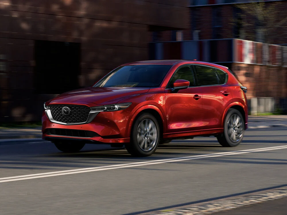 Red Mazda SUV turning onto a cobblestone street